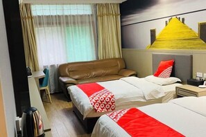 Une chambre d’hôtel avec deux lits, un canapé, un bureau et une fenêtre avec des rideaux.