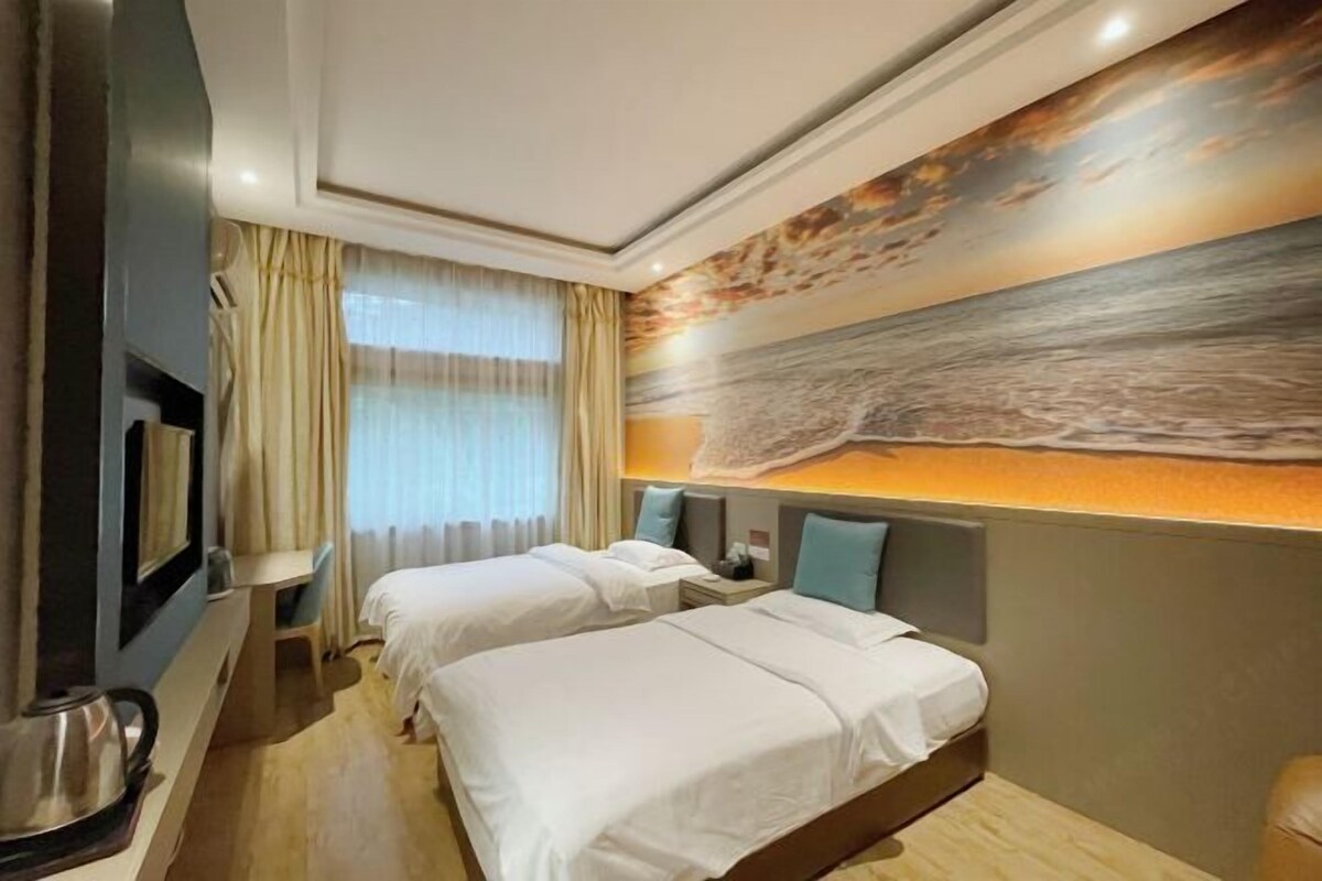 Habitación de hotel con dos camas, un cuadro grande en la pared y una ventana con cortinas.
