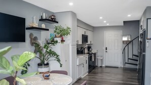 Une cuisine moderne avec des meubles blancs, une table à manger avec des sets de table et une plante en pot.