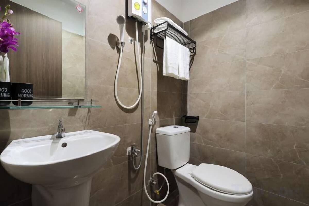 Un baño con lavamanos, inodoro y cabina de ducha con mampara de vidrio.