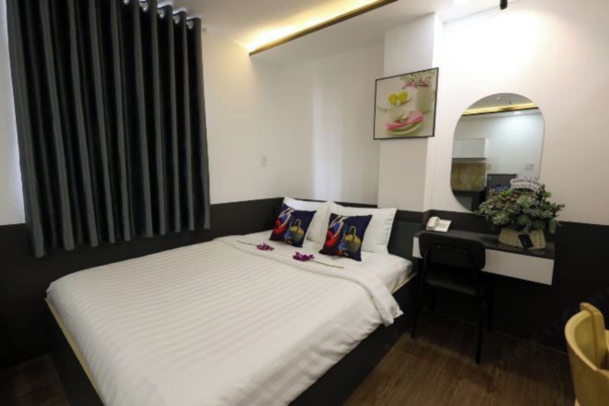 A hotel room with a bed, a desk, and a mirror.