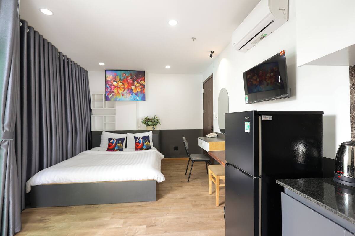 Une chambre d’hôtel moderne équipée d’un lit, d’un bureau, d’une chaise, d’un réfrigérateur et d’un appareil de climatisation.