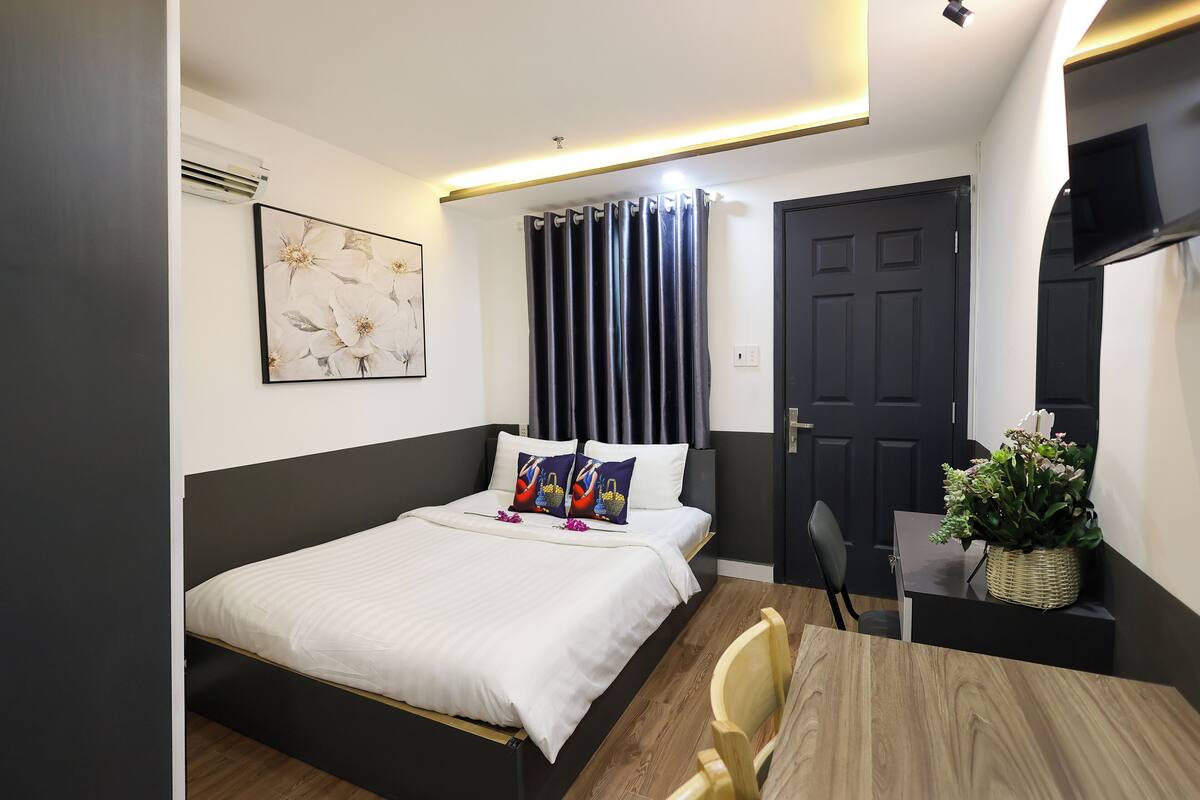 Une chambre à coucher avec un lit, un bureau, une chaise, une plante en pot et une porte.