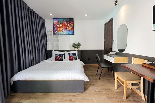 A modern bedroom with a large bed, a desk, and a chair.