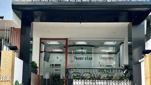 The exterior of Ruby Star Hotel, featuring a modern facade, a staircase leading to the entrance, and potted plants at the base. - Ruby Star Hotel Nam Quoc Cang (Ho Chi Minh City)