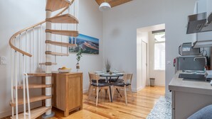 Una cocina moderna con estufa integrada, un comedor con mesa y sillas, y una escalera de caracol.