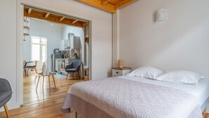Un dormitorio con una cama grande, techo de madera y un área de escritorio al fondo.
