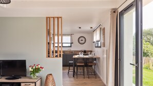 A modern kitchen with a dining area, wooden accents, and a large window. - The Blue Rocks - Maison à moins d'1 km de la plage (Lamballe)