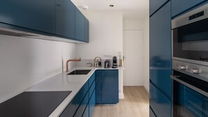 A modern kitchen with blue cabinets, a white countertop, and stainless steel appliances.