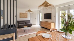 A modern living room with a sofa, dining table, and hanging wicker lamps.