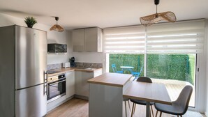 A modern kitchen with a built-in oven, a refrigerator, and a dining area with a table and chairs.