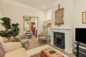 A living room with a fireplace, a television, and a dining area with a table and chairs.