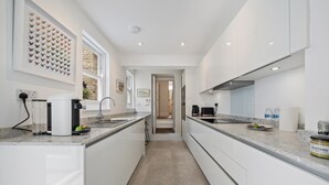 Une cuisine moderne avec des meubles blancs, un plan de travail en granit et une vue sur la salle à manger.