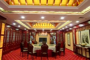 Un salón de banquetes tradicional con una mesa redonda, sillas y un suelo cubierto de alfombra roja.