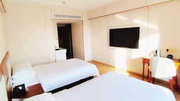 Una habitación de hotel con dos camas, un escritorio, una silla y un televisor.