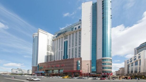 A modern hotel with a prominent curved facade, multiple floors, and a mix of glass and brick architecture. - Harbin Kunlun Hotel (Near Central Street & Harbin Railway Station) (Harbin)