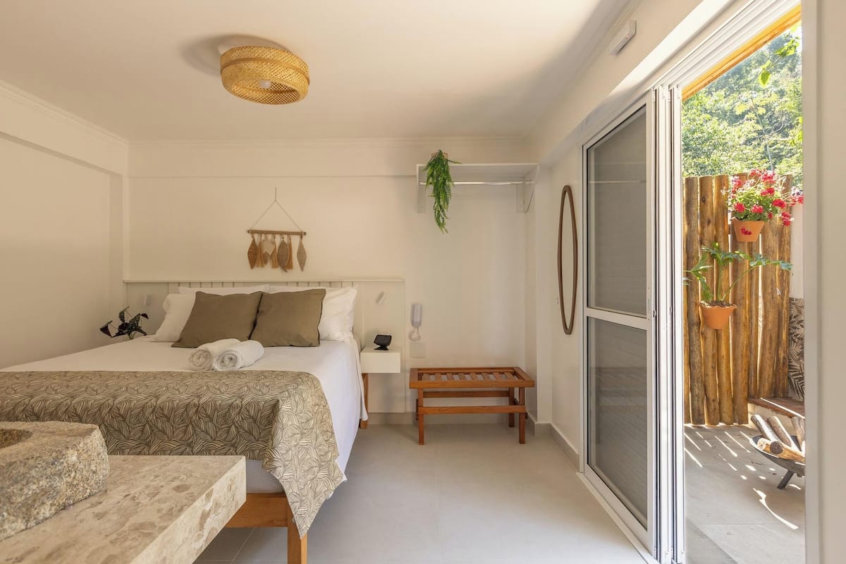 A bedroom with a bed, bedside table, and a hanging plant.