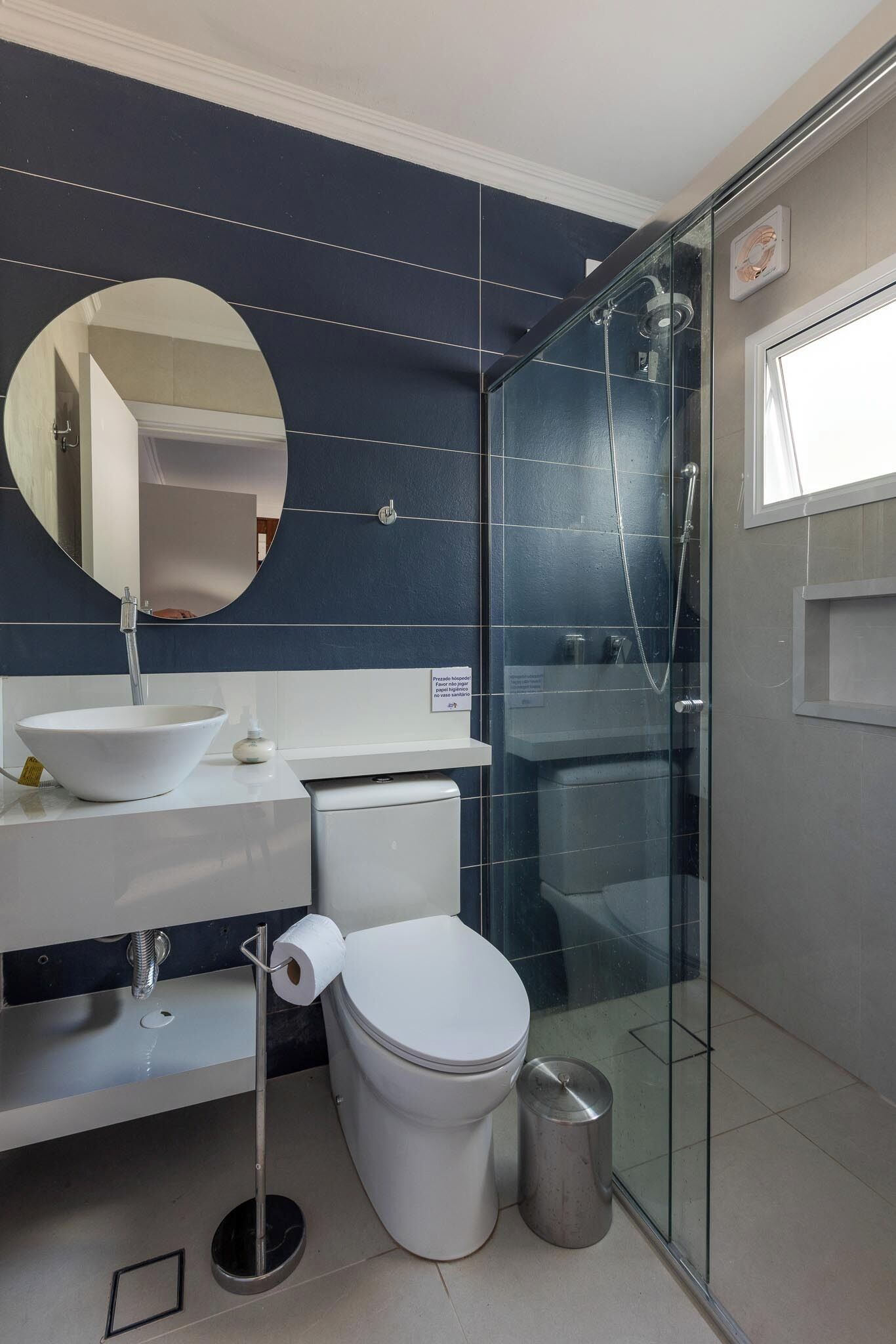 Een moderne badkamer met een douchecabine van glas, een witte wastafel en een toilet.