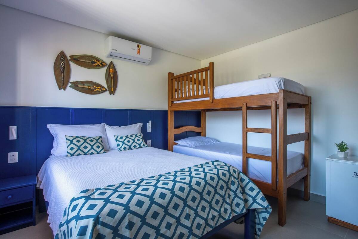A room with a bunk bed, a single bed, and a small cabinet.