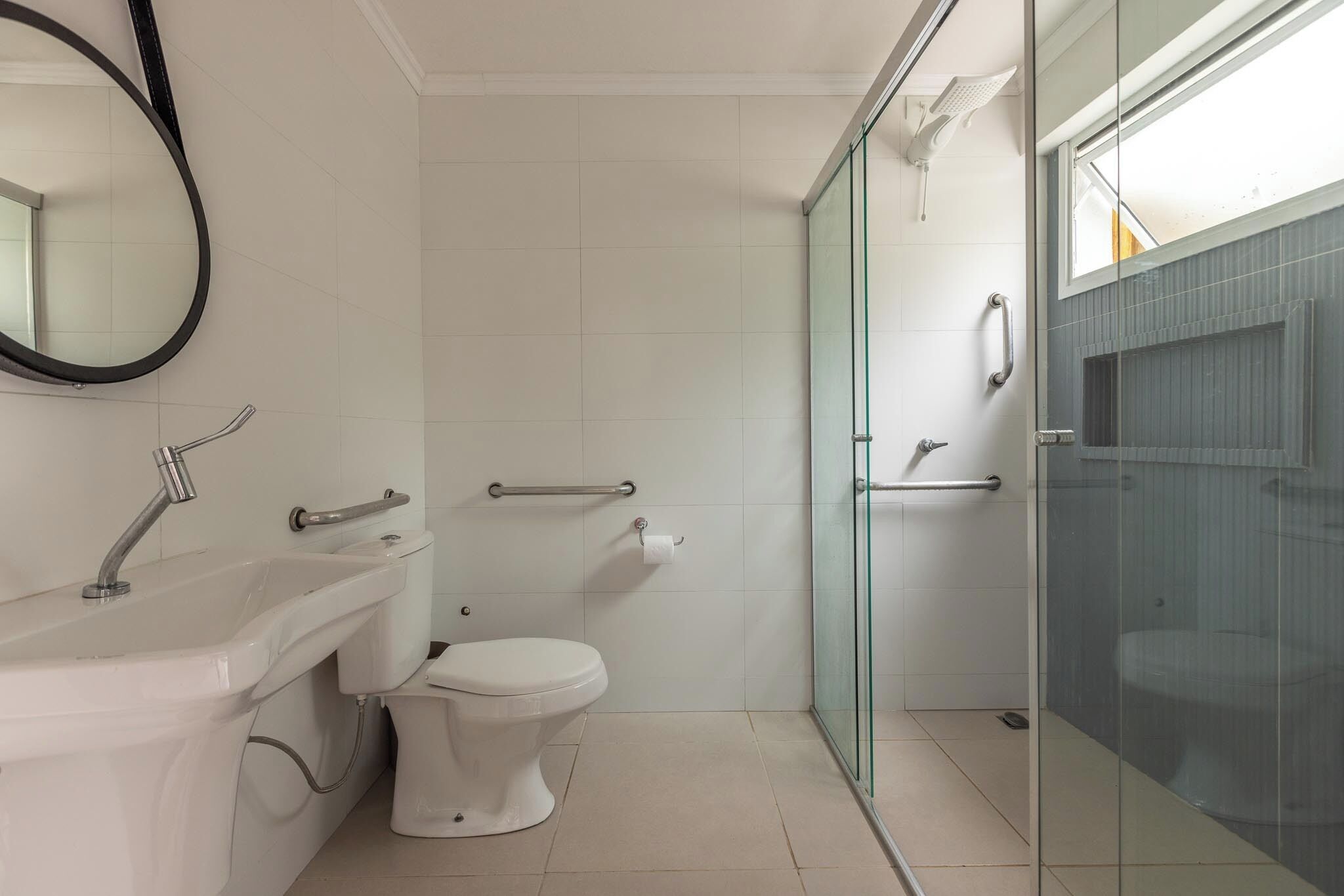 A modern bathroom with a glass shower enclosure, a white toilet, and a sink with a mirror.