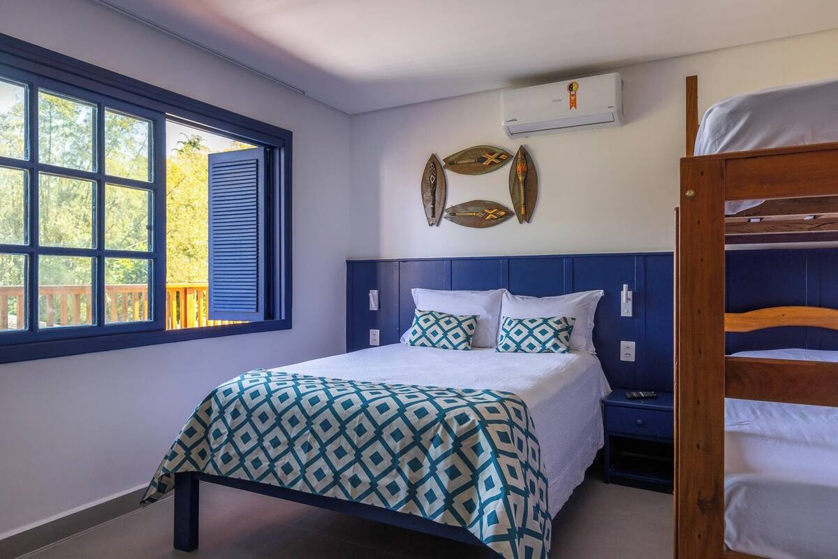 A bedroom with a bed, a window, a bunk bed, and decorative wall art.