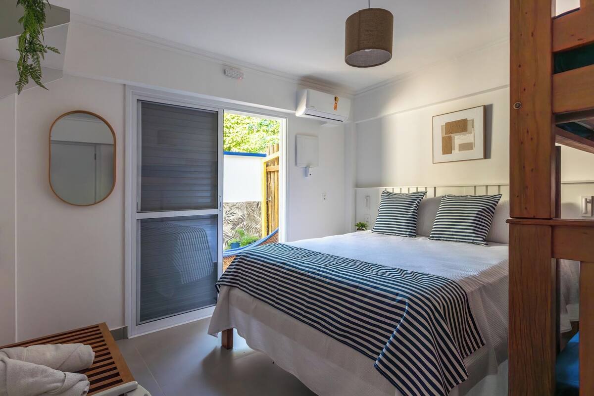 A bedroom with a bed, a window with a view, a mirror, and a ceiling fan.