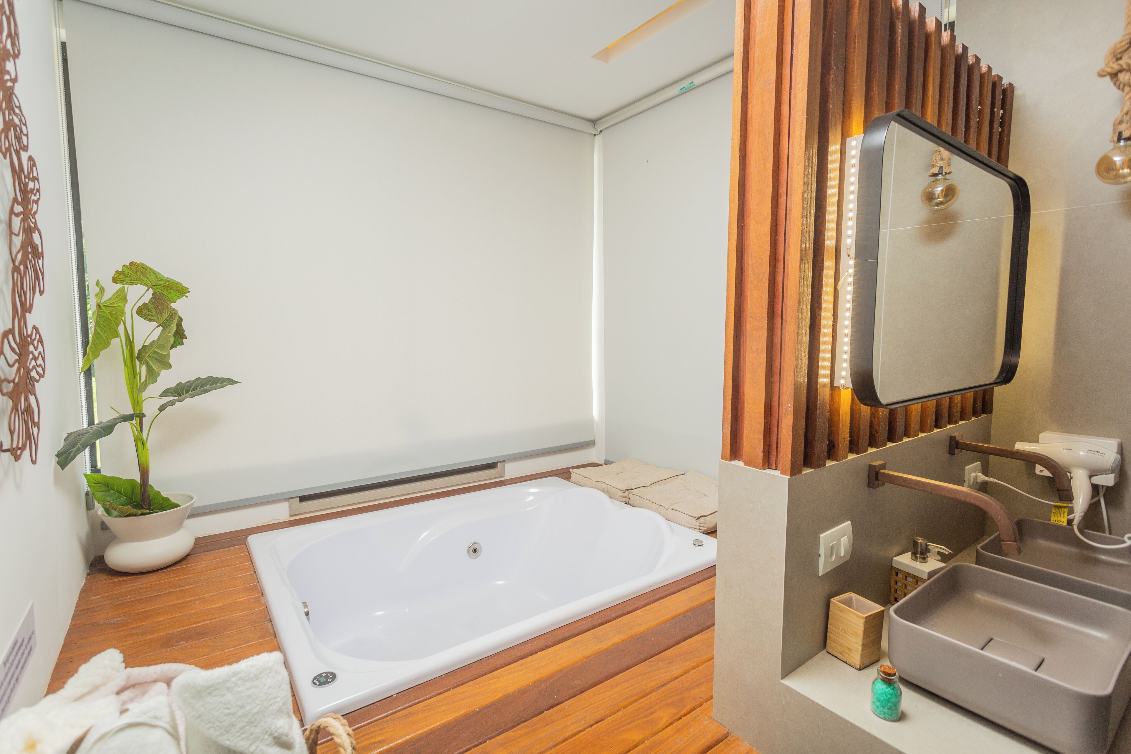 Une salle de bain moderne avec un plancher en bois, une grande baignoire, un lavabo et un miroir.
