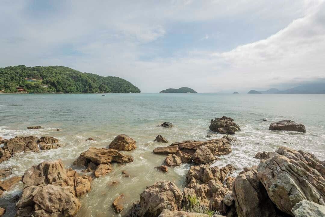 A rocky shoreline with clear water and distant islands.