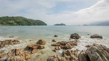 A rocky shoreline with clear water and distant islands.