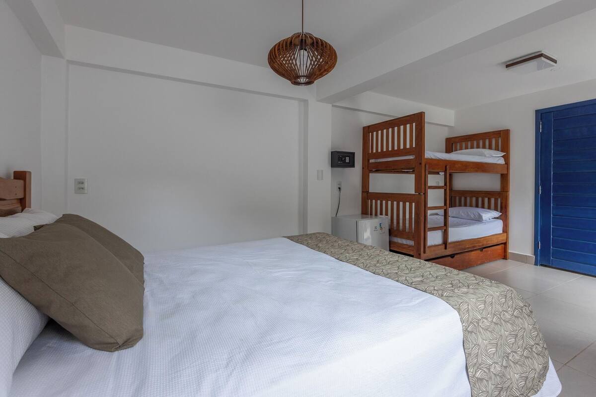 A bedroom with a single bed, a bunk bed, a ceiling fan, and a blue door.