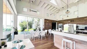 Une cuisine moderne avec des meubles blancs, un îlot central et une vue sur l’extérieur.