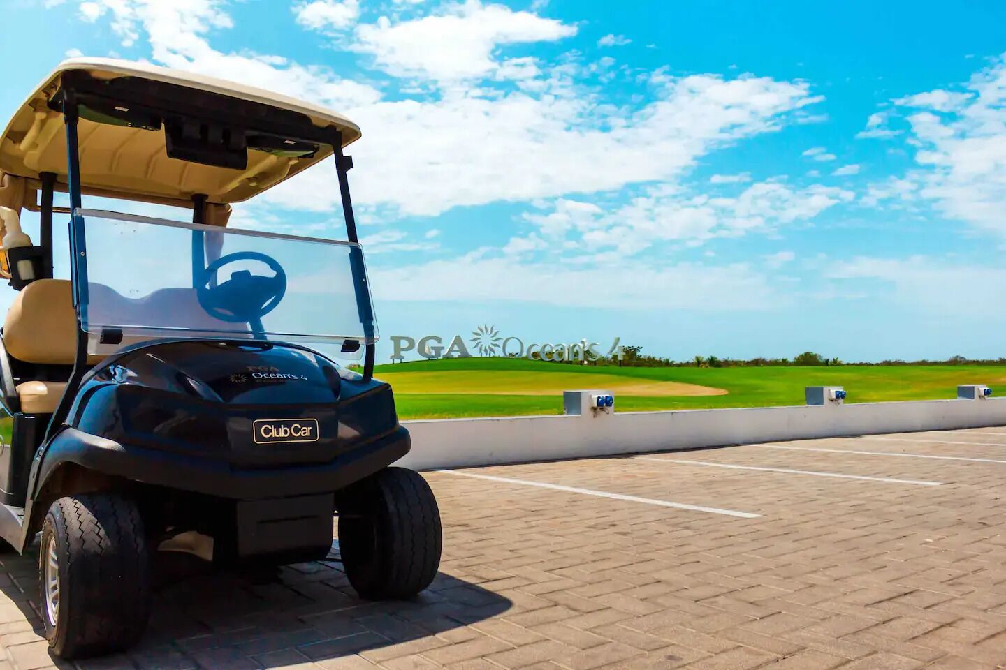En golfbil parkerad på en asfalterad yta, med en skylt med texten ”PGA Oceans 4” i bakgrunden.