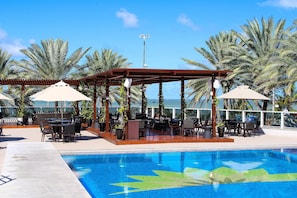 A poolside area with a covered seating area, lounge chairs, and a pool. - Solar Tambaú (João Pessoa)
