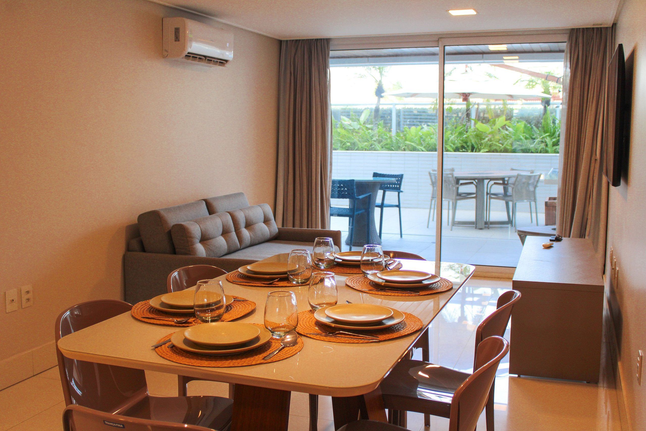 A dining area with a table set for four, a sofa, and a view of the outdoors.