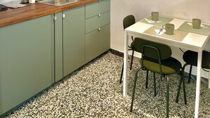 Una cocina compacta con lavabo, armarios y un comedor con sillas y mesa.