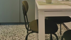 Una cocina moderna con una mesa y sillas blancas, un armario verde y un lavamanos.