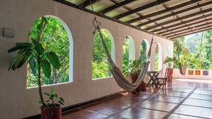 A room with arched windows, a hammock, and potted plants. - HOTEL MINCA LA CASONA (Santa Marta)
