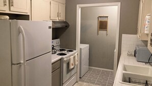 A compact kitchen with a refrigerator, stove, oven, and a small sink. - Movie Matinee Hideaway  (Oklahoma City)