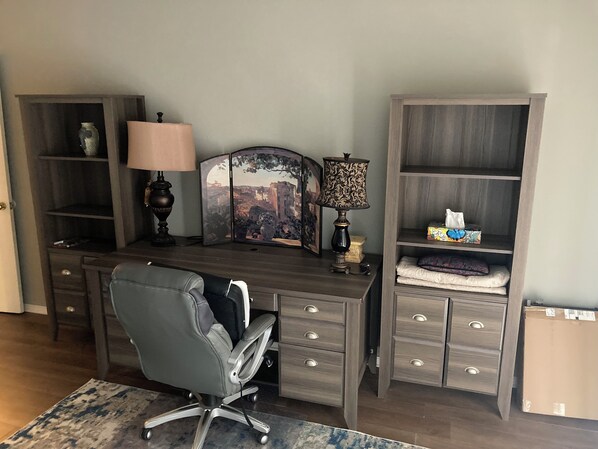 Una oficina en casa con escritorio, dos lámparas, una silla y estanterías empotradas.