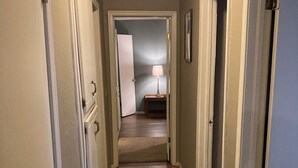 A hallway with patterned carpet, white doors, and a lamp in the distance. - Movie Matinee Hideaway  (Oklahoma City)