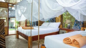 Una habitación con dos camas, suelo de madera y un ventanal con vistas a zonas verdes.