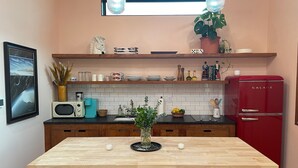 A kitchen with wooden cabinets, a black countertop, a red refrigerator, and a window above the sink.