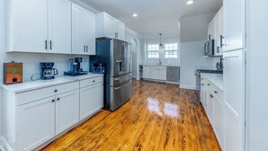 Una cocina moderna con armarios blancos, electrodomésticos de acero inoxidable y piso de madera.