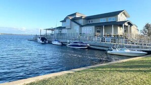 Una propiedad frente al mar con una casa grande, barcos amarrados y una zona ajardinada.
