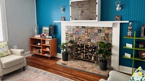 A living room with a blue wall, a fireplace with a tiled surround, a bookshelf, and a sofa.