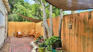 A backyard with a wooden deck, a patio table and chairs, and various potted plants.