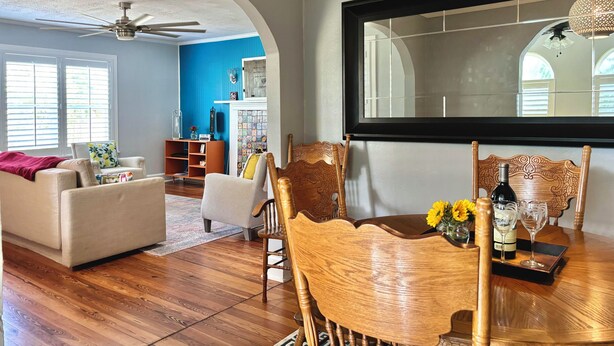 A living room with a dining table, chairs, and a ceiling fan.