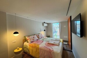 Relax in a spacious bedroom with a large bed, bedside table, and flat-screen TV.