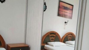 A bedroom with a bed, a nightstand, a wardrobe, and a mirror.