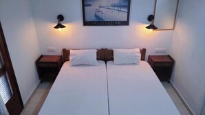 A double bed with two nightstands, a framed picture above, and two wall-mounted lamps.